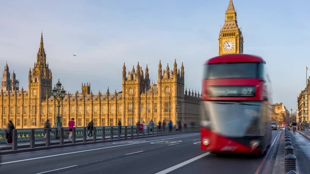 Sunrise time lapse view of the Westminster Bridge with Big Ben clocktower and red bus traffic in golden sunlight in London