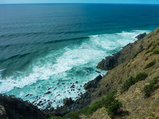 Powerful waves crash against rugged cliffs of Byron Bay, New South Wales, Australia. Dramatic scene of raw natural beauty at Pacific Ocean. Coastal landscape in remote wilderness. Travel destination