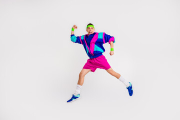 Obraz premium Energetic young man in retro sportswear jumping with joy against a white backdrop