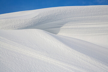 Beautiful winter background with snowy ground. Natural snow texture. Wind sculpted patterns on snow...