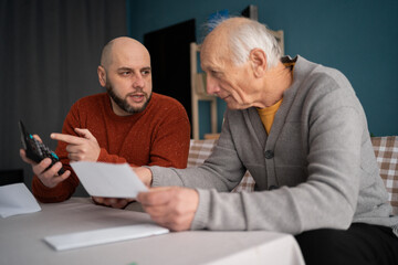 Adult son helping elderly father manage household budget and bills