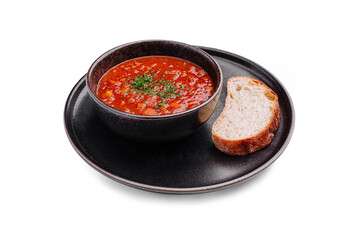 Delicious hearty soup served in a black bowl with a slice of rustic bread on a plate