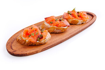 Delicious bruschetta topped with smoked salmon and capers served on a wooden platter