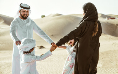 Happy family from Uae spending time in the Dubai desert making a picnic. Kid with the uae flag.