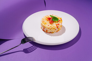 Colorful rice dish garnished with herbs on a modern plate against a vibrant purple background