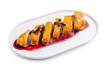 Gourmet dessert featuring sliced pastries drizzled with berry sauce on a white plate