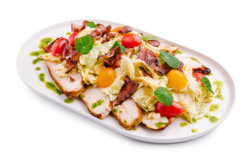 Fresh salad with bacon, mixed greens, and cherry tomatoes on a white platter served in a restaurant
