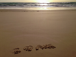 Message of affection for Australia, is written in the sand on a beach in Cooloola, part of the Great Sandy National Park. The sunset over the ocean creates a warm, inviting backdrop