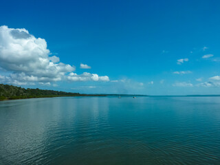 Tranquil seascape in Cooloola, Australia. Calm, reflective waters near the Great Sandy National Park. Two sailboats glide peacefully in the distance, adding sense of serenity to the vast, blue scene.