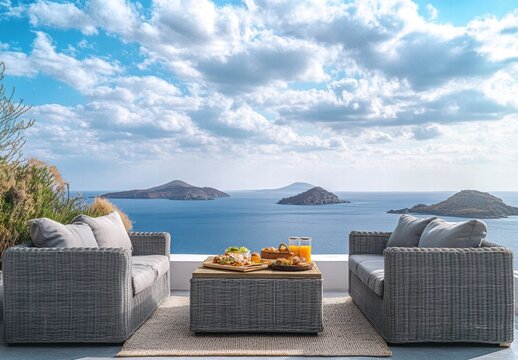 A table with food and drinks is set up on a patio overlooking the ocean