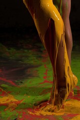 Colorful paint pouring over a leg during an artistic performance in a studio