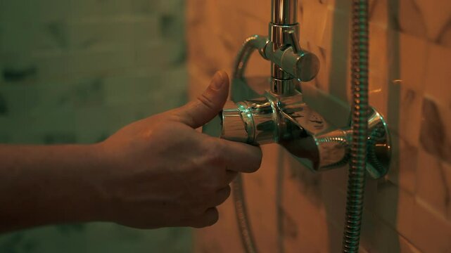 Man hand is opening shower faucet.