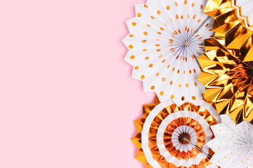 Gold colored paper fans on a pink background with copy space.