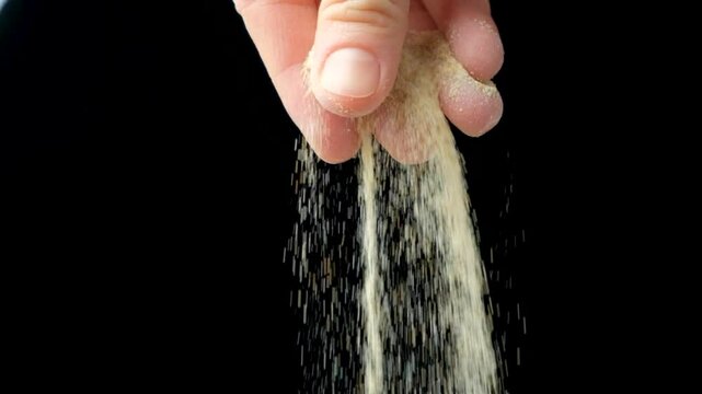 Dried ground garlic seasoning powder, black background, slow motion.