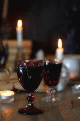 Books, lit candles, red wine, snacks and various deocration on the table. Dark academia or Halloween concept. Selective focus.