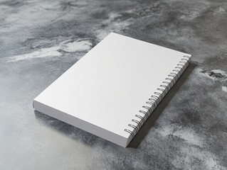 White spiral notebook sits on a grey surface. The notebook is empty and ready to be filled with ideas and thoughts. The grey surface adds a sense of calm and focus to the scene. Concept of money