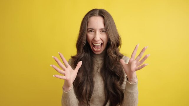 Young woman shouting and making faces on yellow background