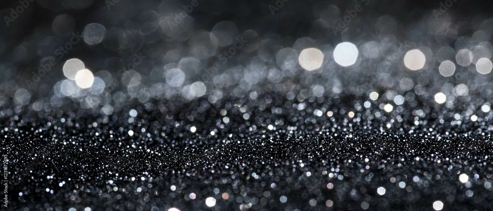 Poster glitter and light particles create a subtle texture over a dark background