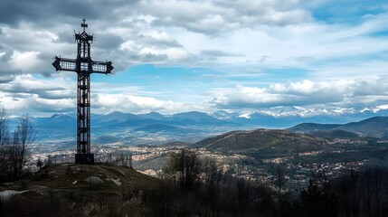 A tall cross with its base on the ground, standing in front of distant mountains
