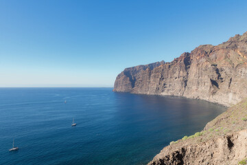 Vue panoramique des falaises de Los Gigantes à Tenerife, surplombant l'océan Atlantique. Eau cristalline, relief volcanique imposant et ciel bleu offrent un paysage spectaculaire et naturel.