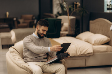Obraz premium A man in a furniture store leafing through a catalogue of fabrics