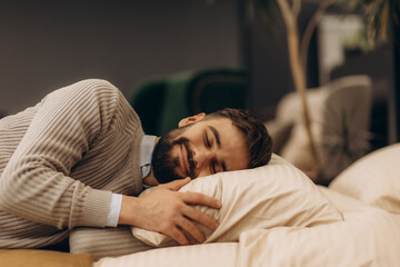 Handsome relaxed man lying on bed with pillow at shop store department