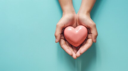 Fototapeta premium Female hands on a blue background holding a pink heart. The concept of donations and family insurance, World Heart Day. valentine's day.