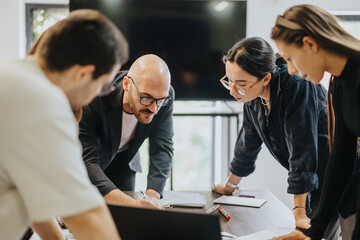 A group of students collaborates on a project with their professor, who offers guidance and support. They are gathered around a table, focused and engaged in a productive academic discussion.