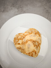 Heart shaped crepes, pancake with white yogurt sitting on white plate, symbolizing romantic morning meal with sweet culinary artistry for Mother's Day Valentines copy space