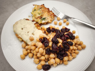 Golden potato pancakes topped with chickpeas, cranberries, drizzling creamy yogurt sauce on rustic wooden surface Galentines day