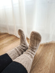 Warm winter moment, woman relaxing in knitted socks near frost covered window and next to the heating overlooking prague cityscape Galentines day
