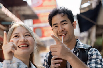 Cheerful Asian friends exploring the city together, enjoying drinks and sharing laughter in a vibrant street setting.