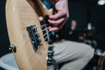 Image capturing the close-up detail of a bass guitar being played during a live music performance,...