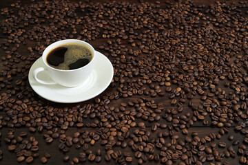 White Coffee Cup with Frothy Coffee and Roasted Coffee Beans on Wooden Surface