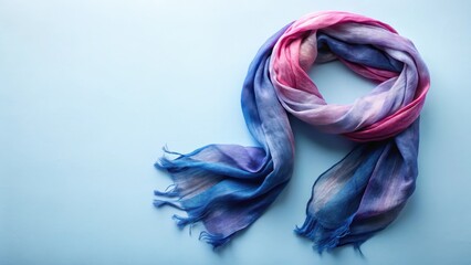 Obraz premium A delicately draped ombre scarf in shades of blue, purple, and pink, showcasing its soft texture and subtle color variations against a light blue background