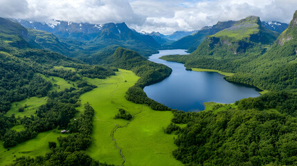 Aerial view Serene lake nestled in lush green valley, snow-capped mountains backdrop