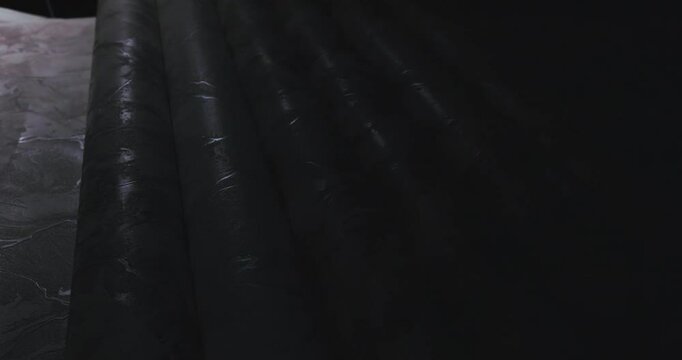 Close-up of a roll of vinyl wallpaper unfolded on a desktop. Abstract drawing on vinyl wallpaper spread on the exhibition table. Light Golden Art. Close-up, macro photography.