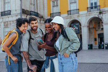Happy tourists using smart phone and laughing in lisbon, portugal