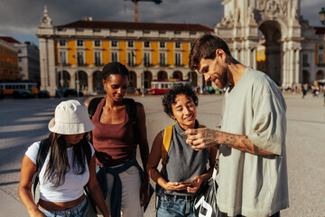 Tourists using smart phones and exploring lisbon city center near famous landmark