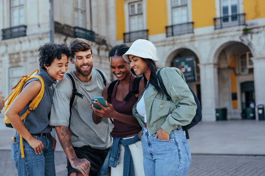 Happy tourists using smart phone and laughing in lisbon, portugal - Powered by Adobe