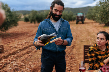 Farmer pouring olive oil on bread in olive grove during harvest time