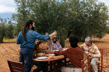 Farmers toasting with wine in olive grove after harvesting olives
