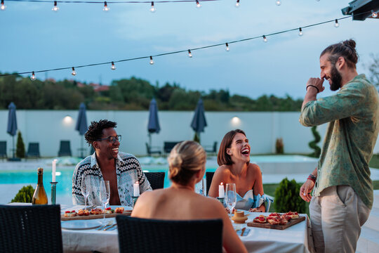 Friends laughing together during a poolside dinner party