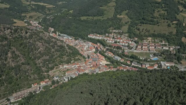 Aerial view revealing ribes de freser's picturesque mountain town nestled in lush pyrenees landscape, showcasing traditional architecture and scenic beauty