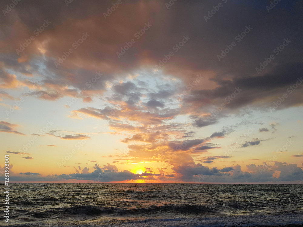 Wall mural colorful sky with dark clouds and bright sun light on sea beach