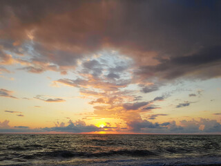 Obraz premium Colorful sky with dark clouds and bright sun light on sea beach
