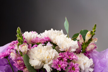 Delicate bouquet of white and pink flowers with dew drops, wrapped in purple packaging. Perfect photo for floristry, wedding designs, cards and romantic compositions. Mother's Day.