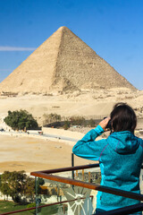 girl standing and taking pictures on the rooftop terrace of a hotel overlooking the pyramids of Giza