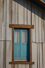 Obraz premium Rustic Wooden House Exterior with a Blue Window. Architectural Design, Vintage Home, Real Estate