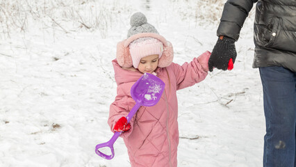 Little girls with her grandfather walk in a snowy forest, have fun together